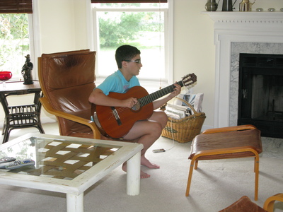 Alec playing accoustic guitar in July