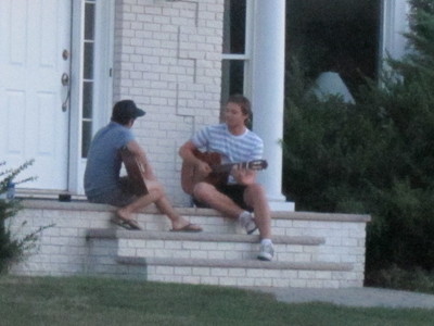 Alec playing guitar with friend on doorsteps